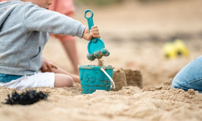 Young child building a sandcastle on the shores of Lake Michigan during a family beach day in Southwest Michigan.